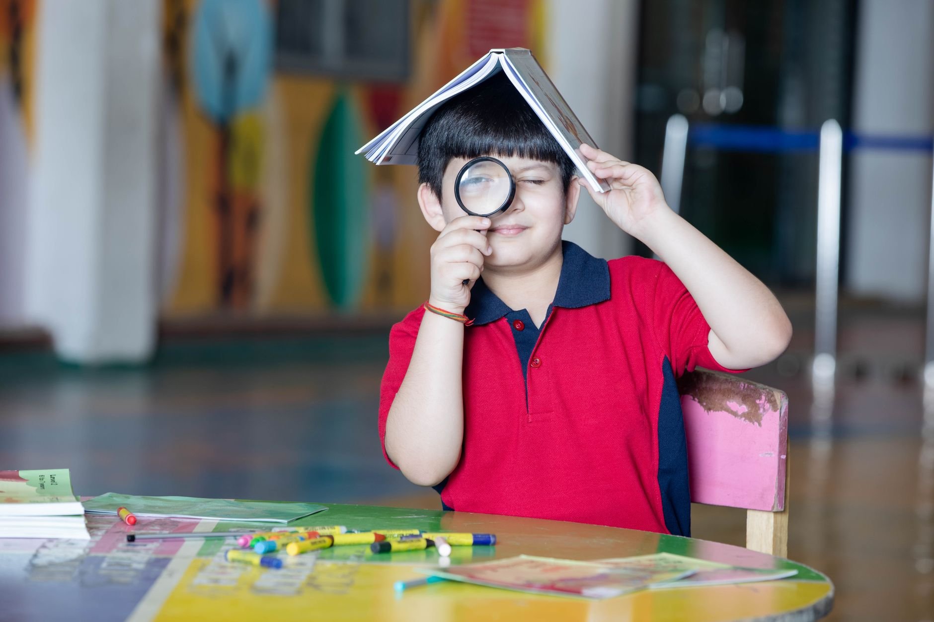 Curious child exploring with a magnifying glass at school desk