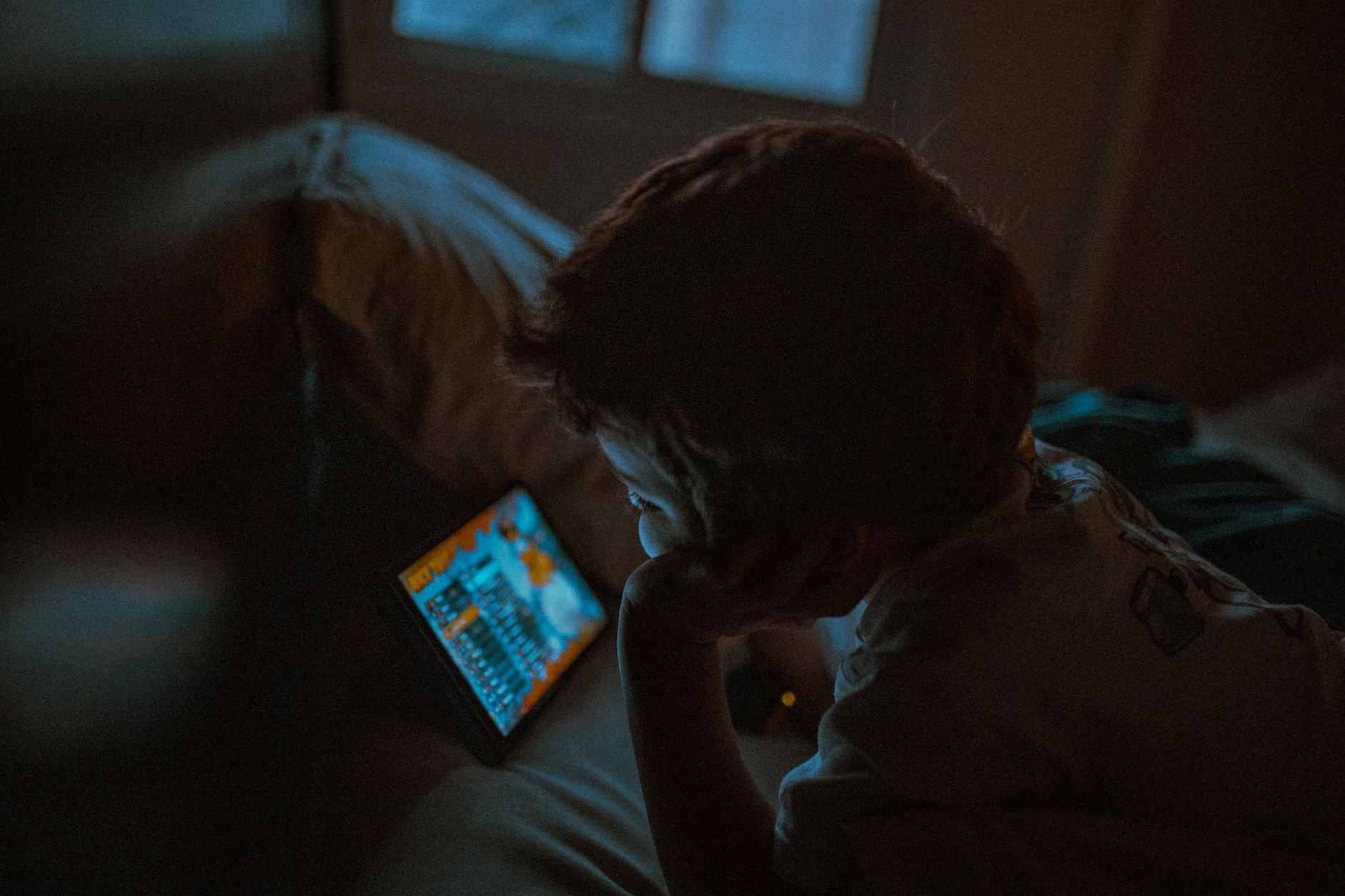 A young child intently watching a tablet in a cozy room